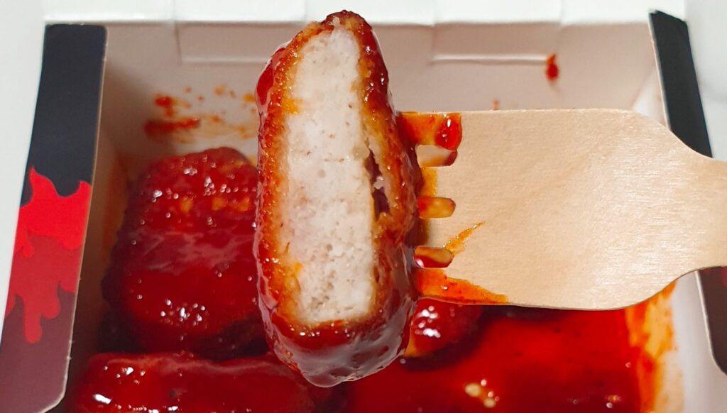 롯데리아 디지게 매운 돈까스의 단면 사진 - 돈가스라는 명칭과 달리 치킨 너겟과 동일한 속살 비주얼을 보여주며 실물 확인 후 느낀 솔직한 실망감을 전달하는 한끼도감의 재료 분석 사진
