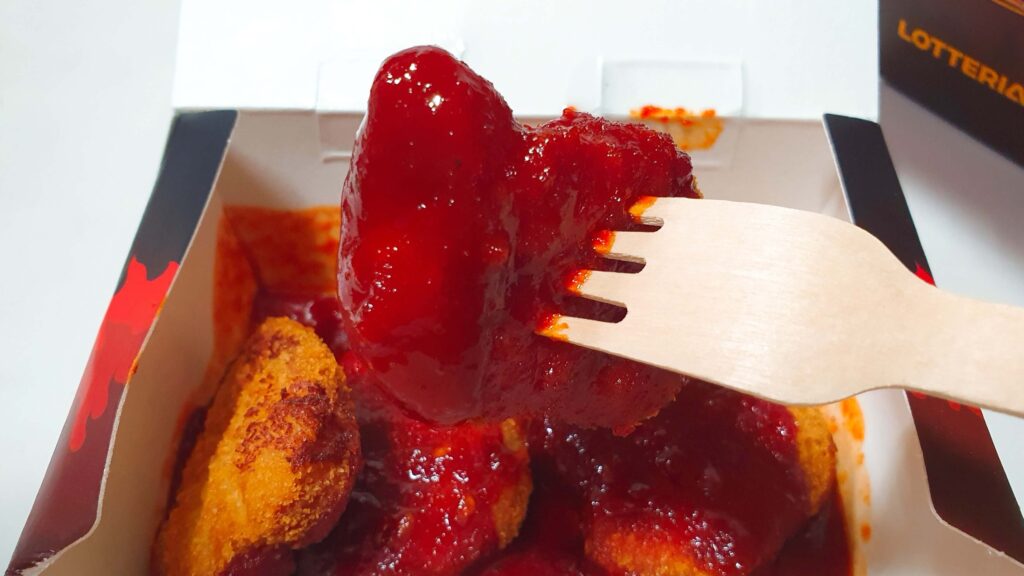 롯데리아 디지게 매운 돈까스 디진다맛의 살벌한 검붉은 소스 광택 - 한 입 베어 물자마자 느껴지는 인위적인 통증과 극강의 매운맛을 경고하는 한끼도감의 시식 실물 사진