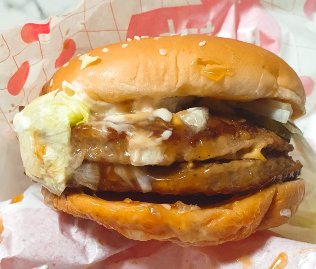 롯데리아 빅불 버거의 두툼한 더블 패티와 녹아내린 치즈가 돋보이는 실물 근접 사진. 일반 불고기버거의 부족한 양을 해결해 주는 묵직한 볼륨감을 통해, 왜 빅불이 만족스러운 선택인지 시각적으로 증명하는 이미지.