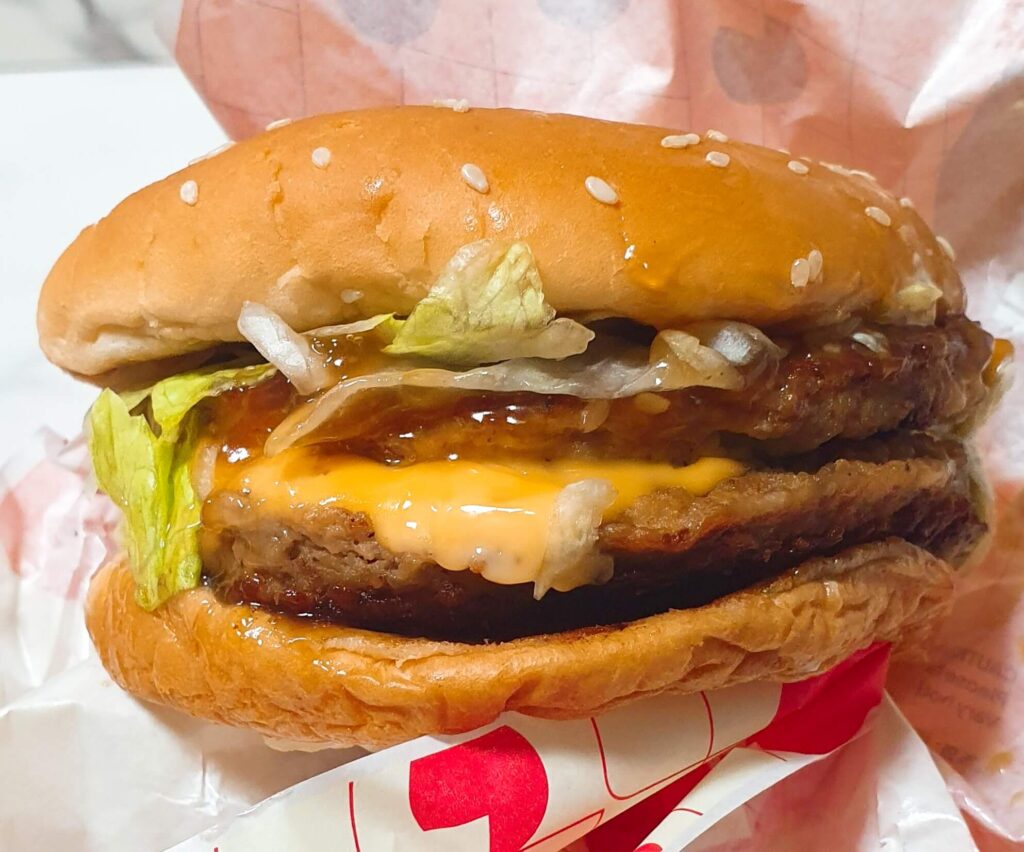 롯데리아 빅불 주문 시 소스를 추가하여 하얀 마요 소스와 달콤한 불고기 소스가 넉넉하게 흘러나오는 실물 근접 사진. 더블 패티의 묵직함에 소스의 촉촉함을 더해 역대급 만족감을 선사하는 '한 끗 차이' 꿀팁 이미지.