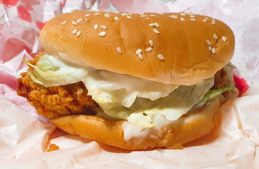 상큼하고 고소한 하얀색 그릭랜치 소스가 곁들여진 롯데리아 통다리 크리스피치킨버거 그릭랜치의 담백하고 바삭한 실물 모습