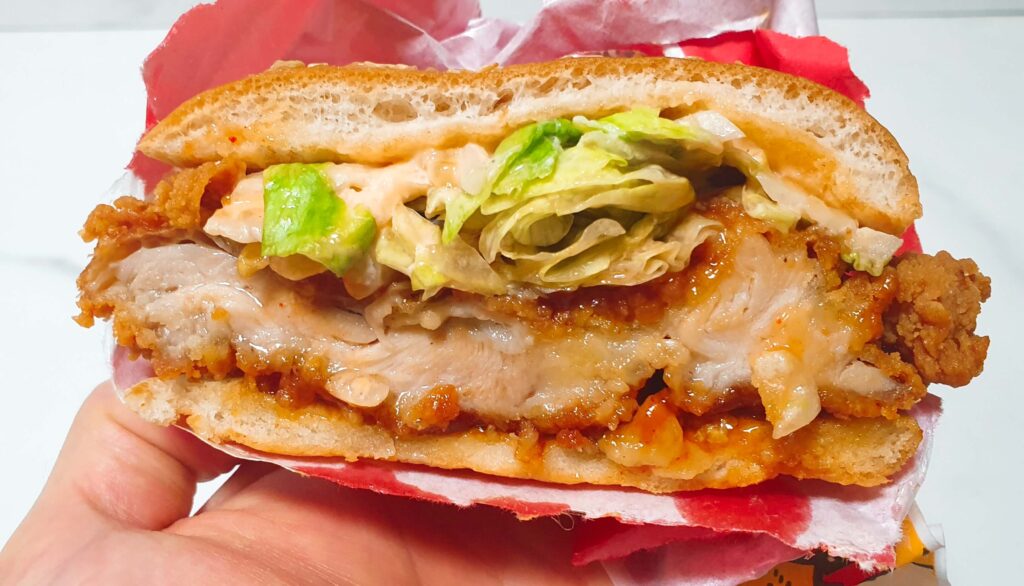 닭다리살의 결이 살아있는 롯데리아 통다리 크리스피치킨버거 파이어핫 패티의 상세 모습과 촉촉함과 바삭함이 공존하는 단면 이미지