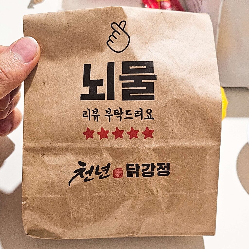 천년닭강정 매장의 리뷰 이벤트 서비스 봉투 사진. 친절한 서비스와 고객 대응을 확인할 수 있는 솔직 후기용 이미지.