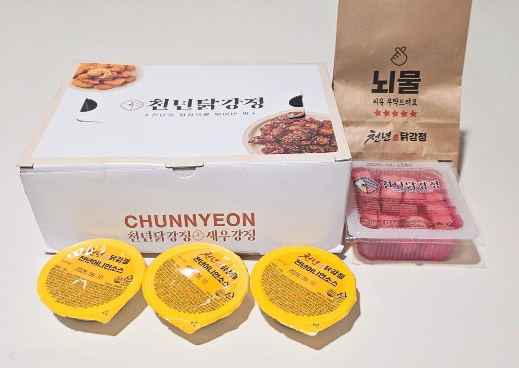 천년닭강정 주문 시 제공되는 전체 구성 사진. 깔끔한 박스 포장과 소스 3개, 서비스 메뉴를 포함한 넉넉한 구성을 확인하여 실패를 방지하는 이미지.
